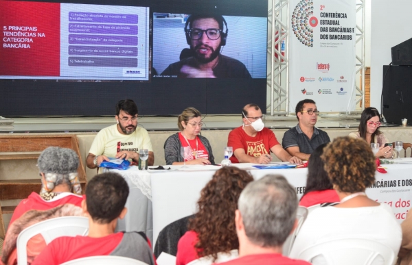 O economista Gustavo Cavarzan (ao fundo, em participação virtual) falou dos impactos das novas tecnologias no trabalho bancário e os desafios de representação do movimento sindical